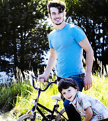 Image showing father learning his son to ride on bicycle outside, real happy f