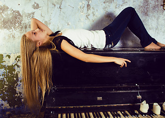 Image showing pretty young blond real girl at piano in old-style rusted interi