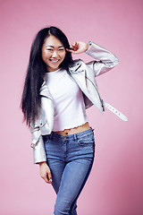 Image showing young pretty smiling asian korean girl wearing modern fashion clothers on pink background, lifestyle people concept 