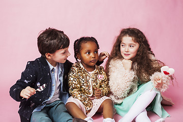 Image showing lifestyle people concept: diverse nation children playing together, caucasian boy with african little girl holding candy happy smiling 