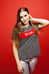 Image showing young pretty emitonal posing teenage girl on bright red background, happy smiling lifestyle people concept