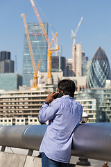 Image showing International businessman talking on mobile phone outdoor in London city, UK.