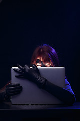Image showing Thief in mask holds laptop