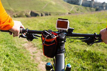 Image showing Hands in orange jacket holding handlebar of a bicycle