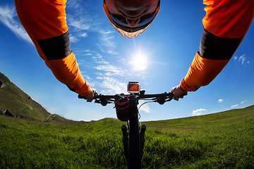 Image showing Hands in orange jacket holding handlebar of a bicycle