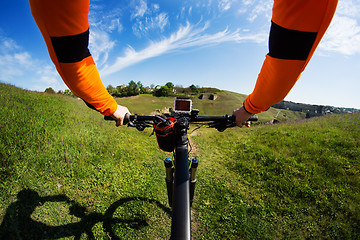 Image showing Hands in orange jacket holding handlebar of a bicycle