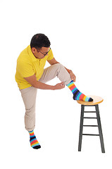 Image showing Man putting on his colorful socks.