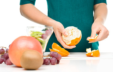 Image showing Cook is peeling orange for fruit dessert