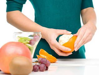 Image showing Cook is peeling orange for fruit dessert