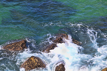 Image showing Marine wave breaks against offshore stone