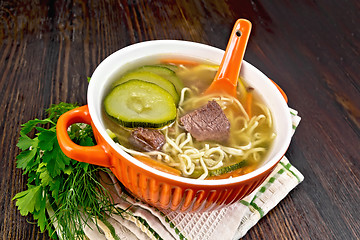 Image showing Soup with zucchini and noodles in red bowl on napkin