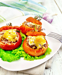 Image showing Tomatoes stuffed with rice and meat with lettuce in plate on lig