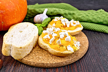 Image showing Bruschetta with pumpkin and basil on dark board