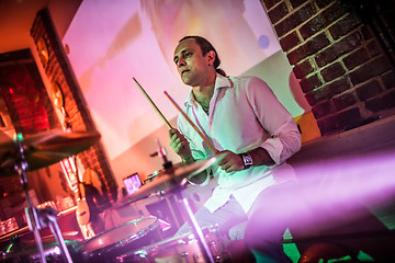 Image showing Drummer playing on drum set on stage.