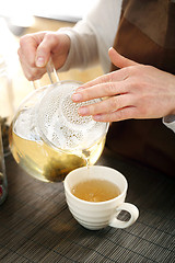 Image showing Blooming tea. The waitress pours tea into a cup.