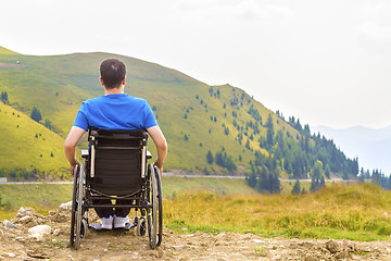 Image showing Young man in a wheelchair enjoying fresh air on a sunny day