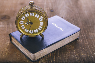 Image showing Holy Bible and old alarm clock on wood table