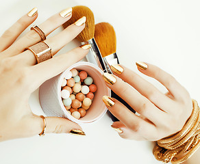 Image showing woman hands with golden manicure and many rings holding brushes,