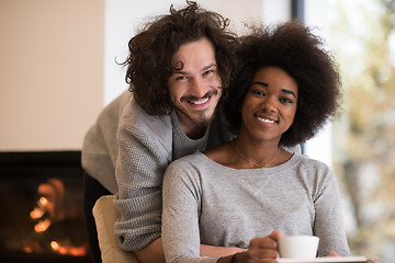 Image showing multiethnic couple hugging in front of fireplace