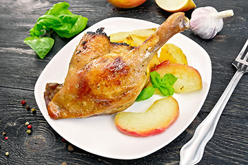 Image showing Duck leg with apple and potatoes on black board