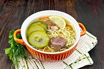 Image showing Soup with zucchini and noodles in red bowl on wooden board