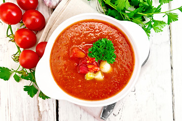 Image showing Soup tomato in white bowl with vegetables and parsley on board t