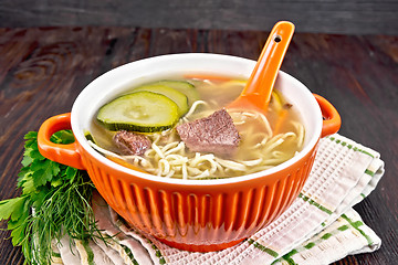 Image showing Soup with zucchini and noodles in red bowl on dark board