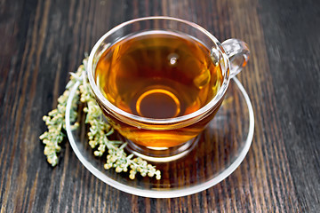 Image showing Tea with gray wormwood in glass cup on dark board