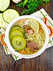 Image showing Soup with zucchini and noodles in red bowl on board top