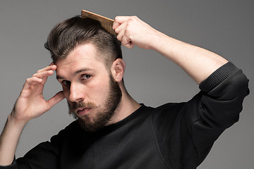 Image showing Portrait of stylish handsome young man combing his hair