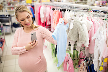 Image showing pregnant woman taking picture of baby clothes