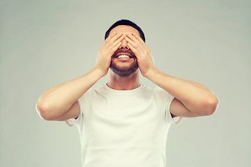 Image showing smiling man closing his eyes over gray background