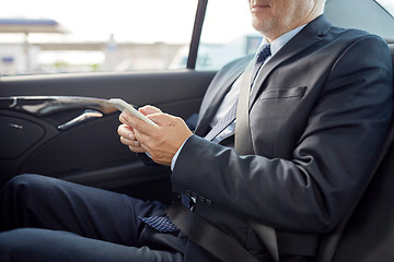 Image showing senior businessman texting on smartphone in car