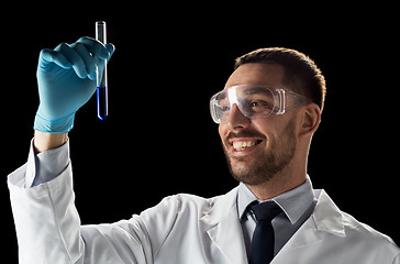 Image showing smiling scientist in safety glasses with test tube