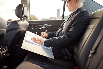 Image showing senior businessman with papers driving in car