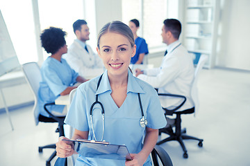 Image showing happy doctor with clipboard over group of medics