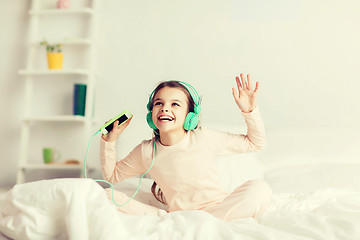 Image showing girl sitting on bed with smartphone and headphones