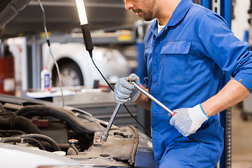 Image showing mechanic man with wrench repairing car at workshop