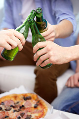 Image showing close up of friends clinking beer bottles at home