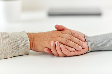 Image showing close up of old man and young woman holding hands