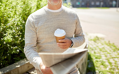 Image showing senior man with coffee reading newspaper outdoors