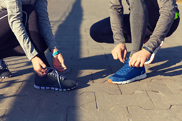 Image showing close up of couple tying shoelaces outdoors