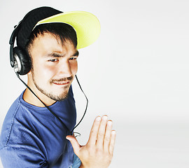 Image showing young asian man in hat and headphones listening music on white b