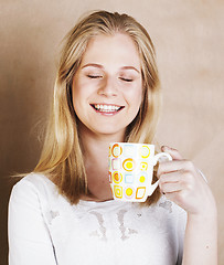 Image showing young cute blond girl drinking coffee close up on warm brown bac