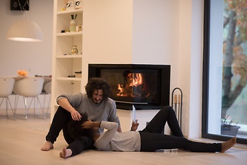 Image showing multiethnic couple using tablet computer on the floor