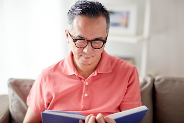 Image showing man sitting on sofa and reading book at home