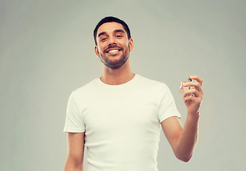 Image showing smiling man with male perfume over gray background