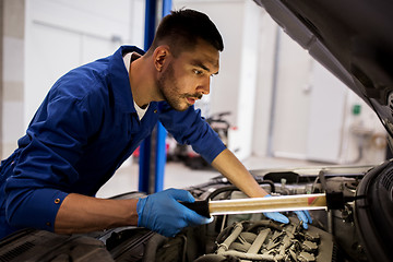 Image showing mechanic man with lamp repairing car at workshop