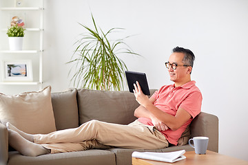 Image showing man with tablet pc sitting on sofa at home