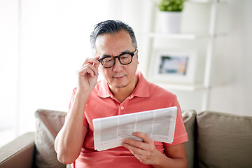 Image showing happy man in glasses reading newspaper at home